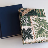 Two custom handmade journals with unique covers—one in classic navy blue and the other featuring a tropical Hawaiian-inspired botanical fabric, showcasing the craftsmanship at Kuro's Workshop.