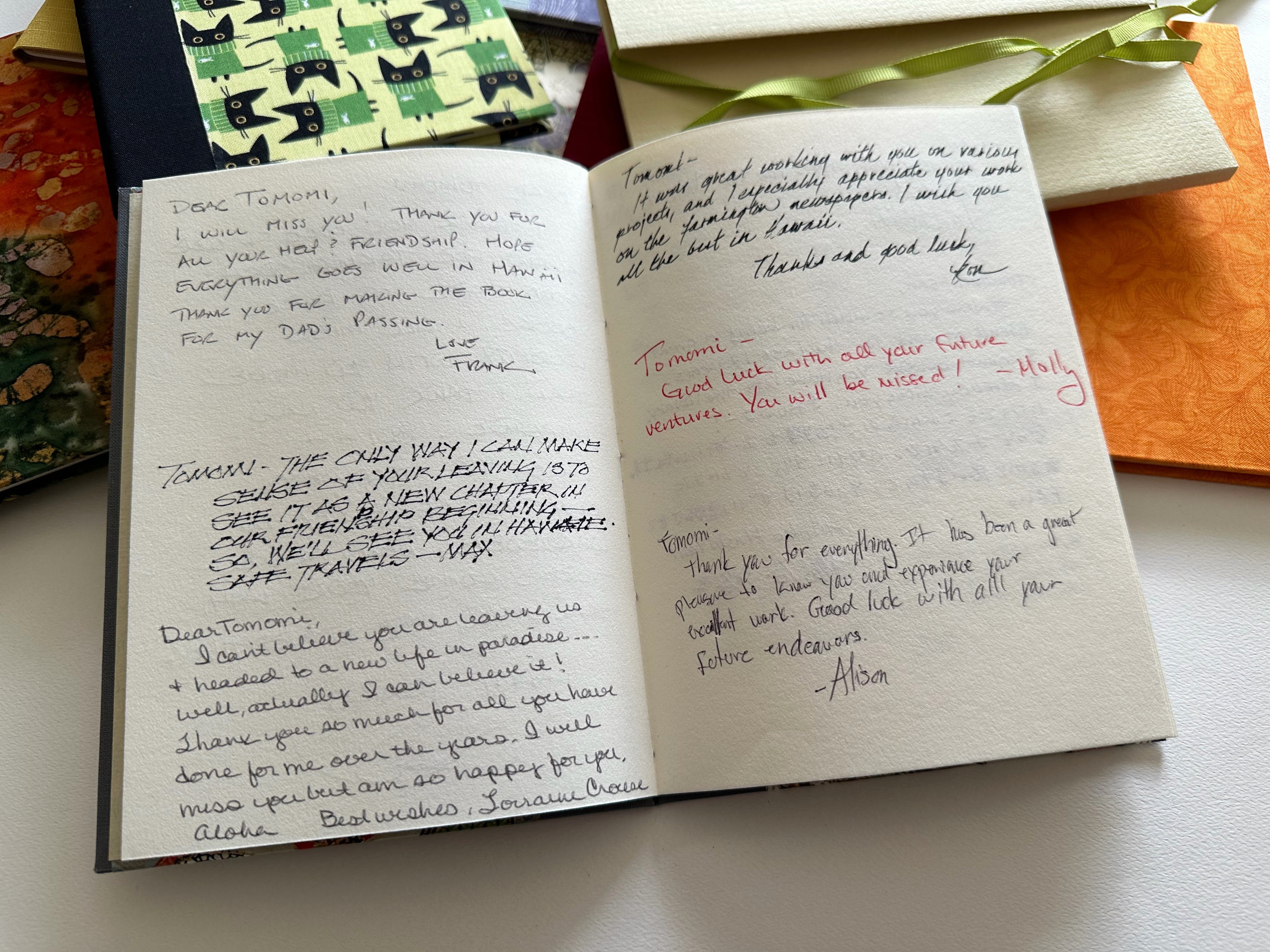 An open handmade keepsake card filled with handwritten farewell messages from colleagues and friends. The high-quality, textured pages provide a heartfelt space for meaningful notes, making this a perfect personalized gift for special occasions like retirements, departures, or milestone celebrations. Surrounding keepsake cards showcase various available designs.