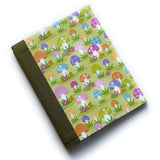 The Merry Mushroom DIY Bookmaking Kit features a whimsical, colorful mushroom pattern on a vibrant green background, accented with playful florals. This handmade bookbinding kit includes all the necessary materials to create a unique journal, perfect for nature lovers, fantasy enthusiasts, and those who appreciate fun, botanical-inspired stationery.
