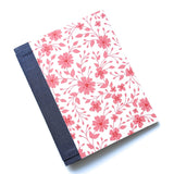The Pink Blossom DIY Bookmaking Kit features a delicate pink floral pattern on a crisp white background, complemented by a deep blue book spine. This handmade bookbinding kit includes all the essentials to create a beautifully crafted journal, ideal for writers, artists, and stationery enthusiasts who love elegant floral aesthetics.