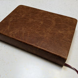 This "after" image showcases a beautifully restored antique book, now featuring a rich brown leather cover with a smooth, reinforced spine and a new ribbon bookmark. Expert book restoration has transformed the fragile, deteriorating volume into a durable and elegant keepsake, preserving its history while enhancing its longevity for generations to come.