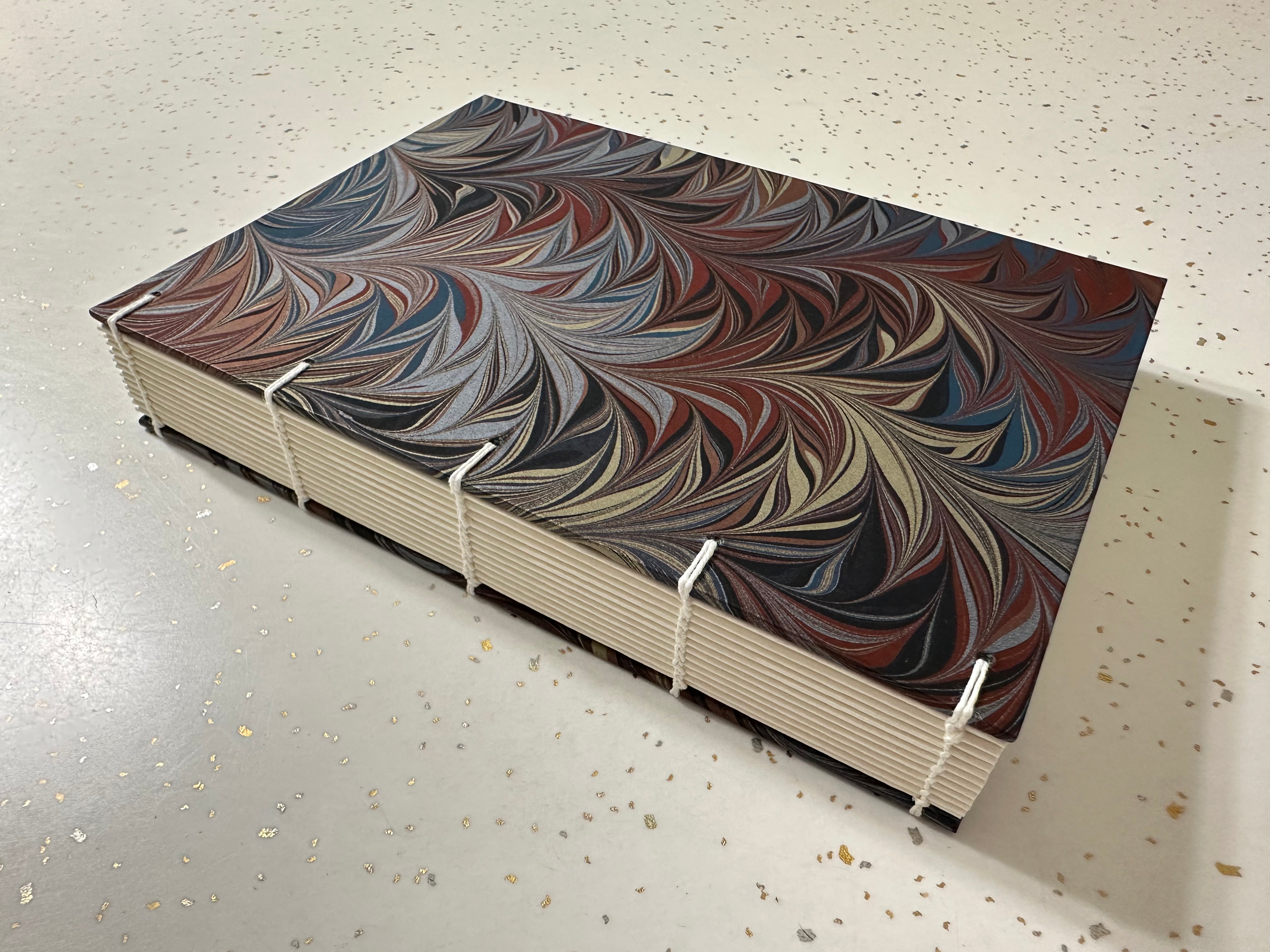 Coptic style book with Renato Crepaldi Marbled paper used for the cover on a speckled surface