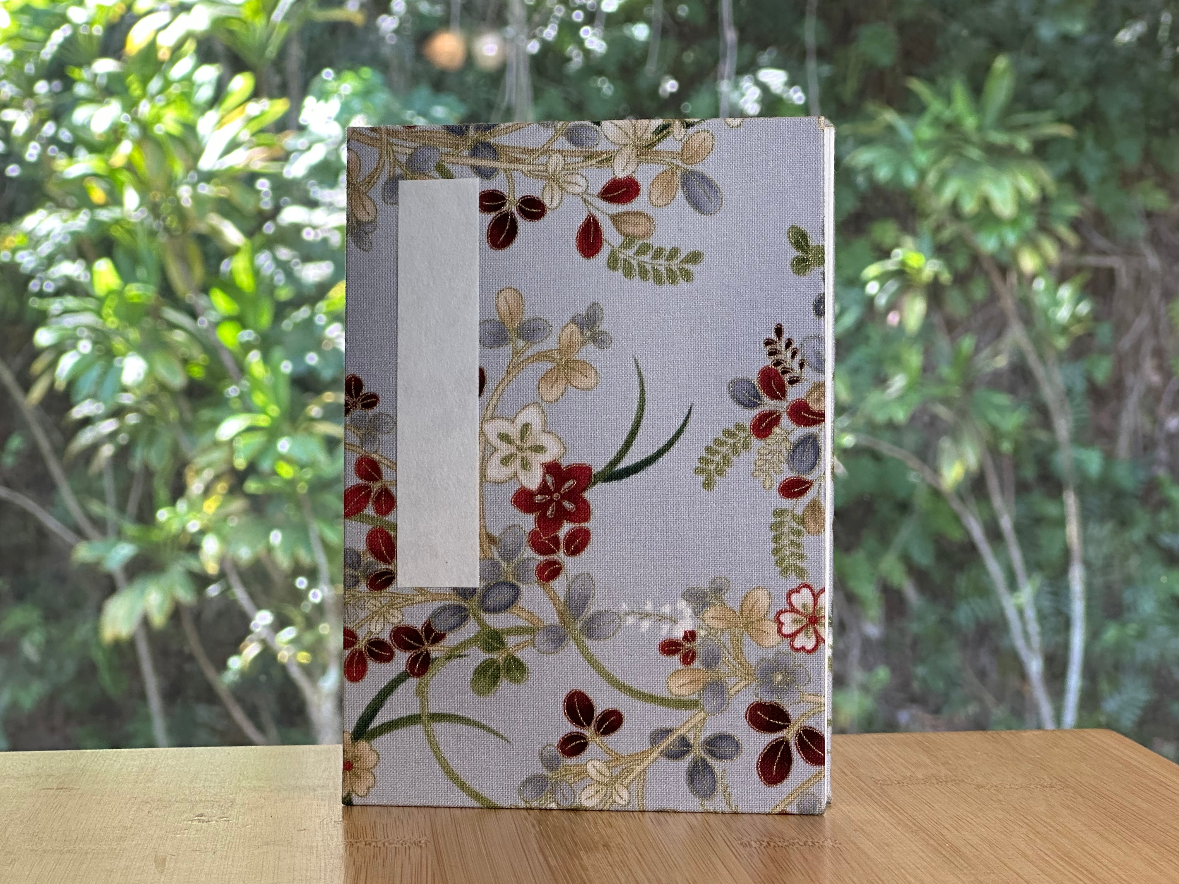 Floral-patterned Goshuincho on a wooden surface with a blurred green background