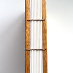 A close-up view of the Mango Wood Coptic Journal, showcasing its exposed spine.  The sturdy wooden covers are paired with durable thread stitching, allowing the journal to lay flat when open. This unique handmade book is perfect for journaling, sketching, or creative writing enthusiasts who appreciate craftsmanship and longevity.