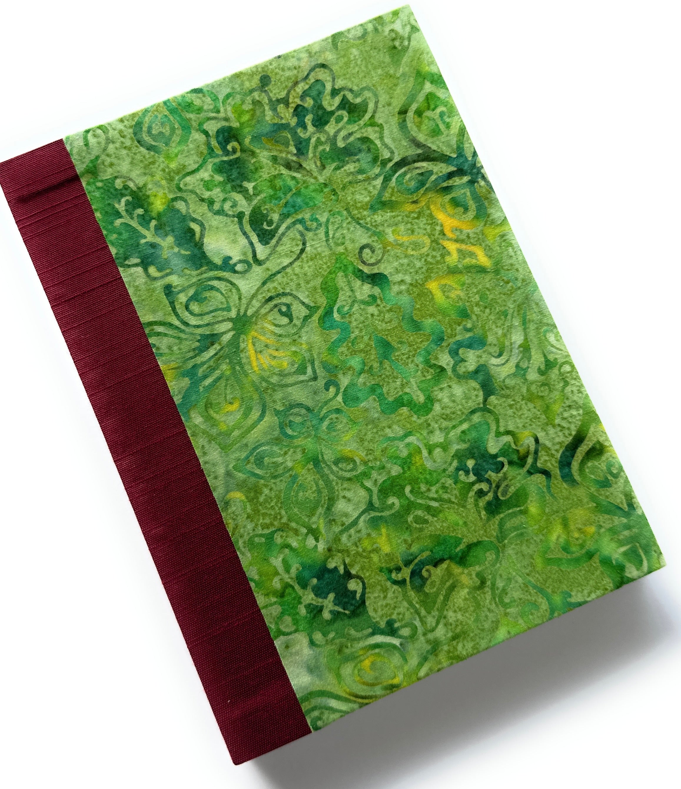This handcrafted fabric journal features a vibrant green batik cover with intricate abstract patterns, giving it a tropical and artistic appeal. The red book cloth spine provides a striking contrast while ensuring durability. Designed for writers, artists, and journal enthusiasts, this unique handmade notebook is perfect for journaling, sketching, or note-taking.