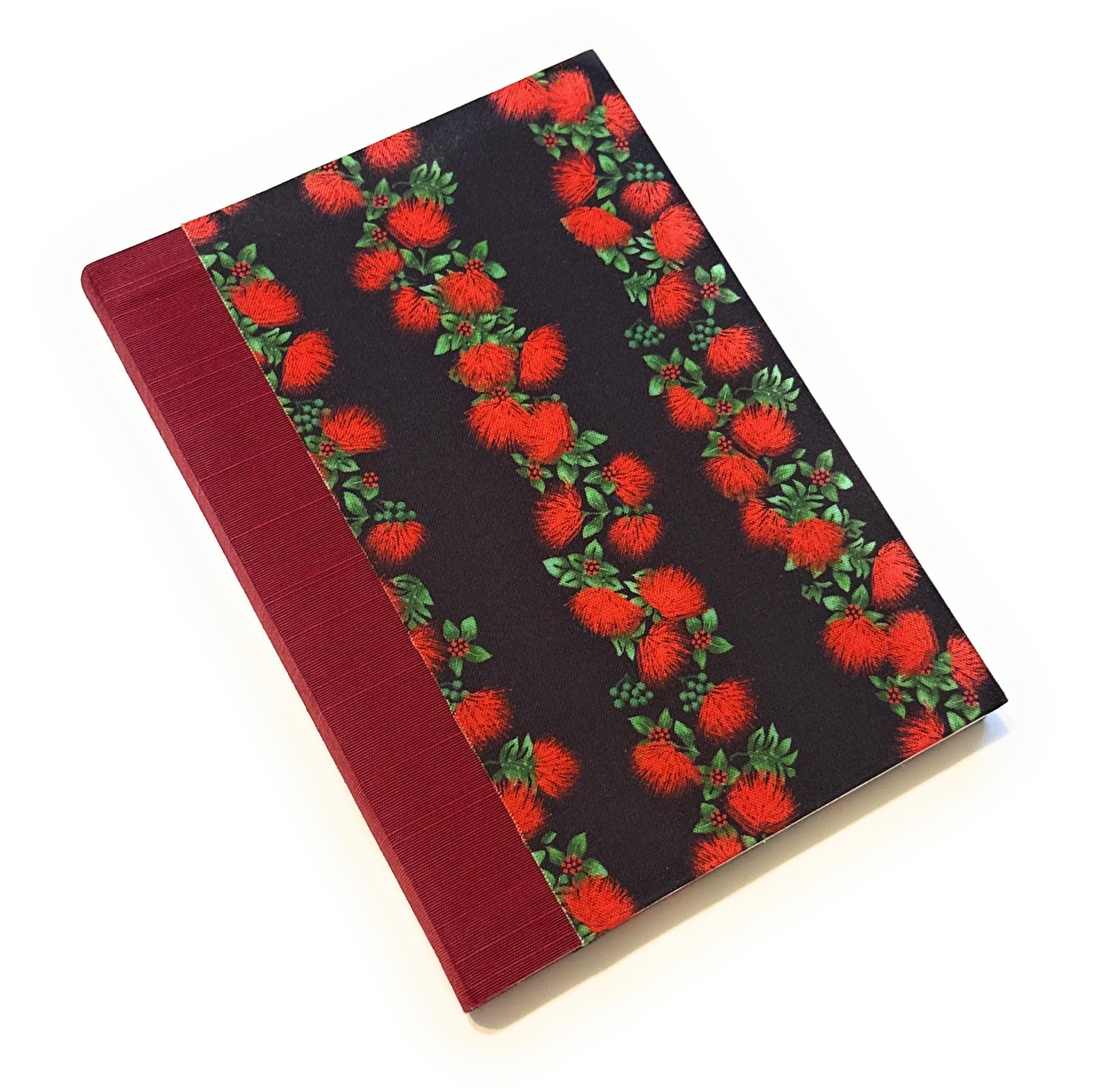 This handmade Hawaiian journal features a stunning ʻŌhiʻa Lehua floral fabric cover, showcasing bold red blossoms and lush green leaves against a deep black background. The spine is wrapped in a rich red book cloth, adding a refined touch. Crafted with high-quality materials, this tropical-inspired notebook is perfect for writing, journaling, or sketching. A unique gift for stationery lovers, writers, and artists, it celebrates Hawaiian culture and craftsmanship.
