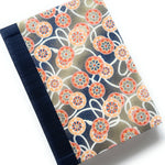 This handcrafted journal features an intricate Japanese cartwheel pattern in warm orange, red, and blue tones, set against a beige backdrop. A sturdy navy book cloth spine adds durability and elegance, making this notebook ideal for journaling, note-taking, or creative writing. Inspired by traditional Japanese textiles, this unique handmade journal is a perfect gift for writers, artists, and stationery lovers.