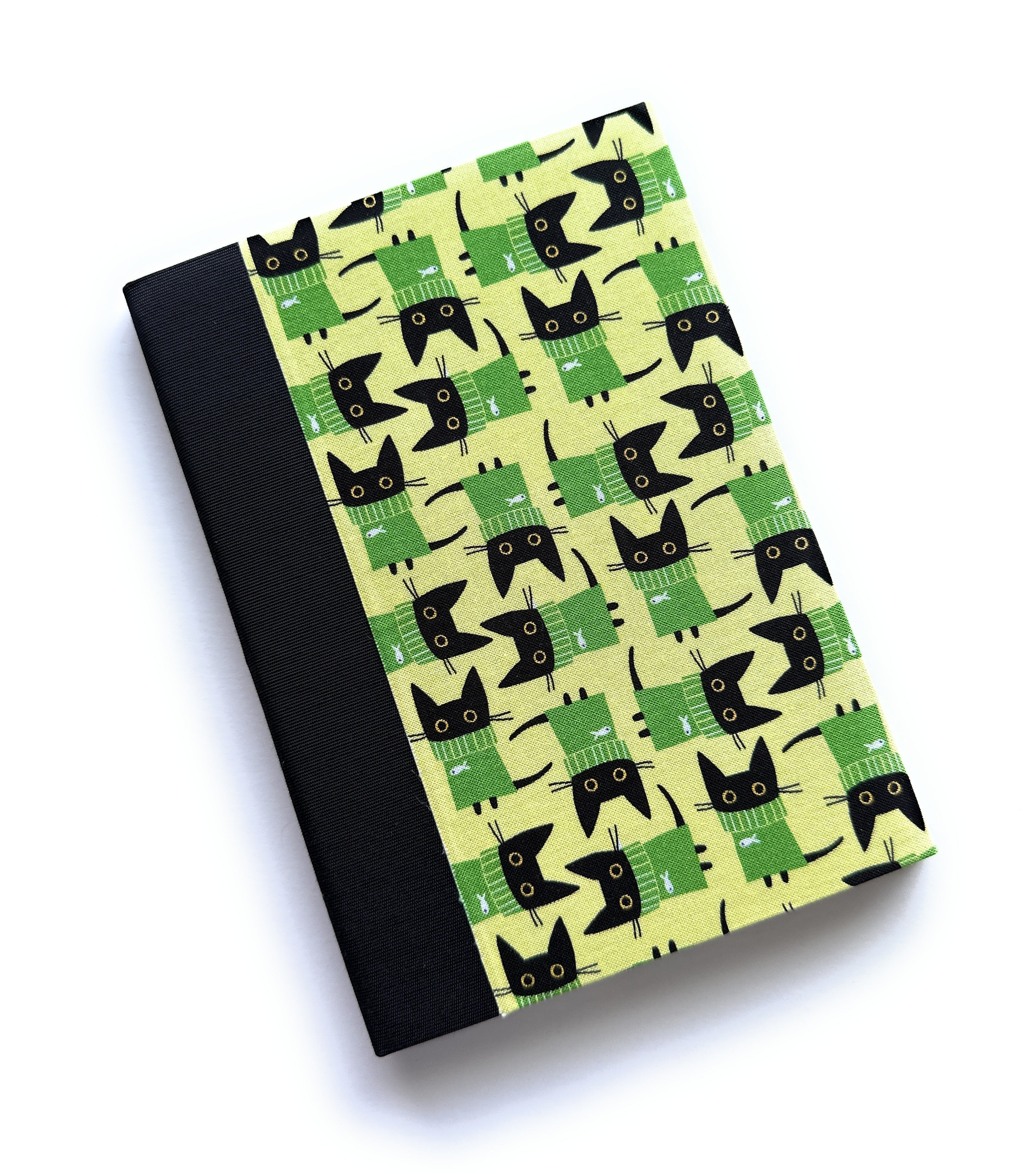 The Kuro Neko keepsake card features a playful pattern of black cats wearing green sweaters on a soft yellow background. Paired with a sleek black book cloth spine, this handcrafted card is perfect for cat lovers, adding a touch of charm and whimsy to heartfelt messages and cherished notes.