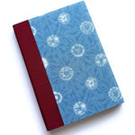 The Yuki keepsake card features a serene blue fabric cover with a delicate shibori-inspired snowflake pattern, complemented by a rich burgundy book cloth spine. Handcrafted for meaningful messages, this unique card is perfect for commemorating special moments, heartfelt sentiments, and cherished memories.