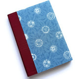 The Yuki keepsake card features a serene blue fabric cover with a delicate shibori-inspired snowflake pattern, complemented by a rich burgundy book cloth spine. Handcrafted for meaningful messages, this unique card is perfect for commemorating special moments, heartfelt sentiments, and cherished memories.