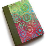 A handbound card featuring vibrant circular batik patterns in pink, green, and aqua hues, with an olive green cloth spine - designed as a keepsake card