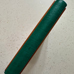 Green leather spine of a Leather Quarter Binding on a speckled surface