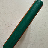 Green leather spine of a Leather Quarter Binding on a speckled surface