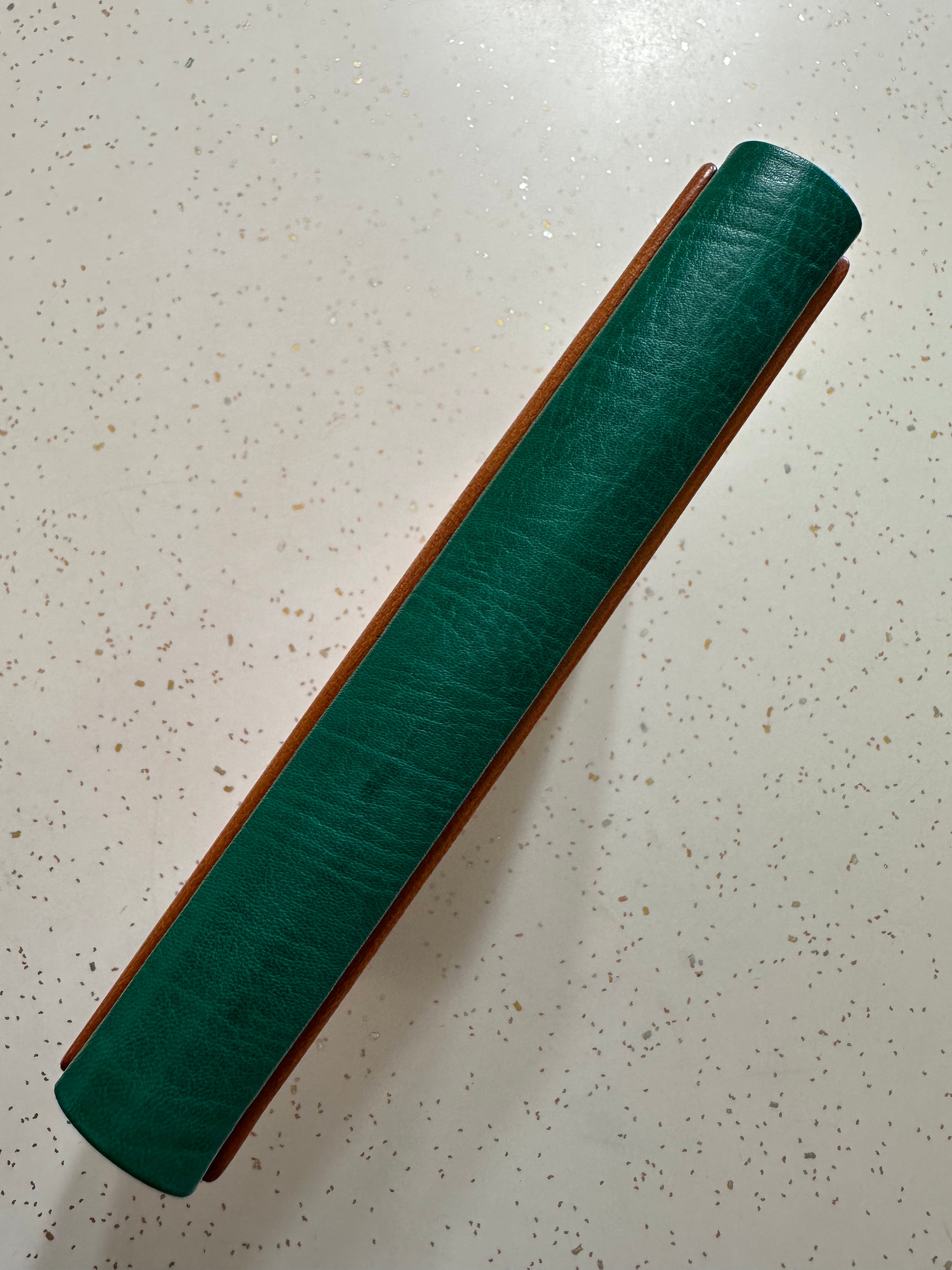 Green leather spine of a Leather Quarter Binding on a speckled surface