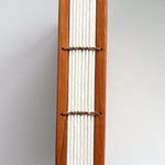 A close-up view of a handmade Lychee wood Coptic journal, showcasing its beautifully exposed Coptic stitch along the spine. The durable wooden covers frame the high-quality, cream-colored pages, bound together with natural waxed thread for flexibility and strength. This binding style allows the journal to lay completely flat, making it ideal for artists, writers, and journal enthusiasts who appreciate traditional bookbinding craftsmanship.