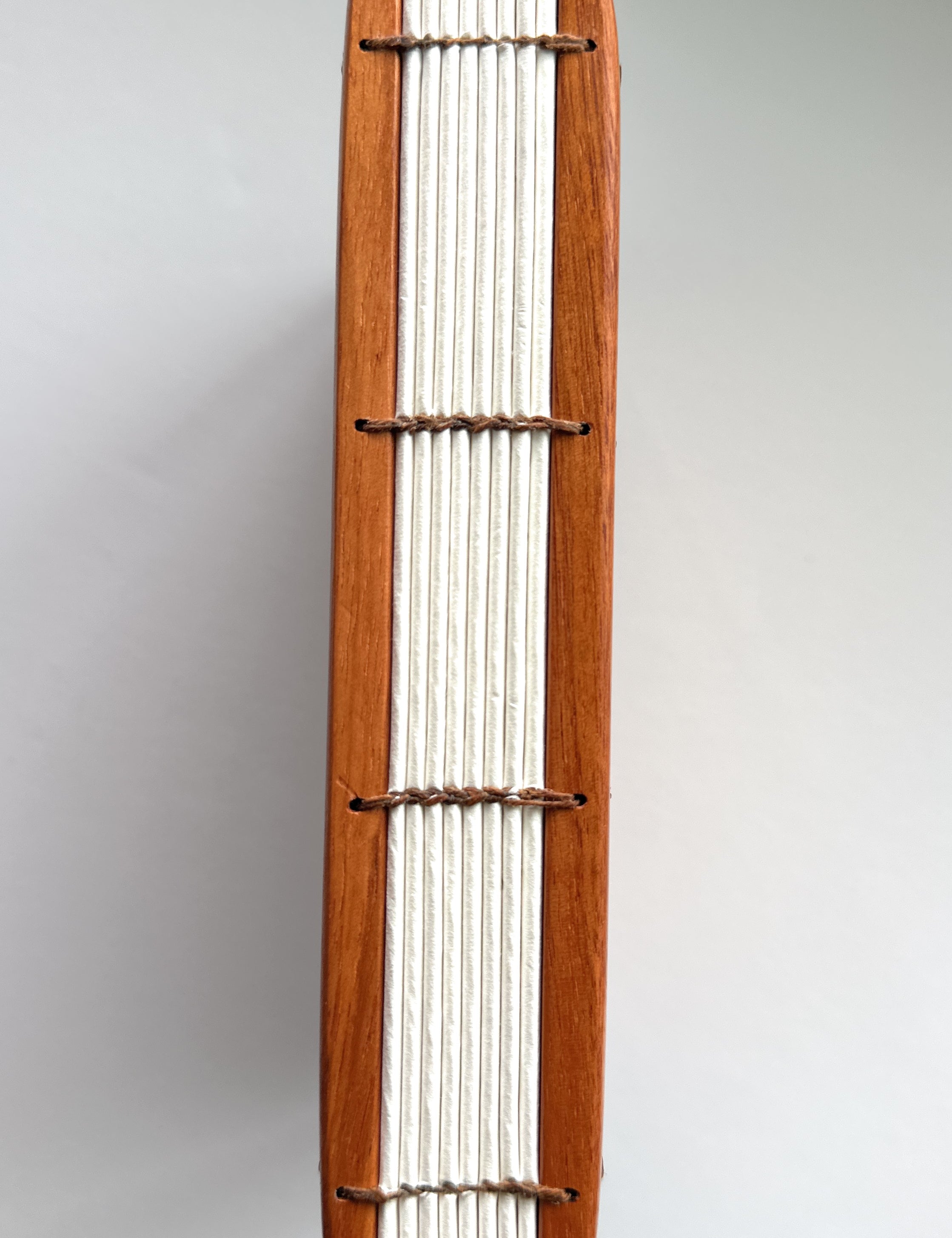 A close-up view of a handmade Lychee wood Coptic journal, showcasing its beautifully exposed Coptic stitch along the spine. The durable wooden covers frame the high-quality, cream-colored pages, bound together with natural waxed thread for flexibility and strength. This binding style allows the journal to lay completely flat, making it ideal for artists, writers, and journal enthusiasts who appreciate traditional bookbinding craftsmanship.