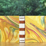 Colorful marbled miniature notebook with orange accents on a wooden surface