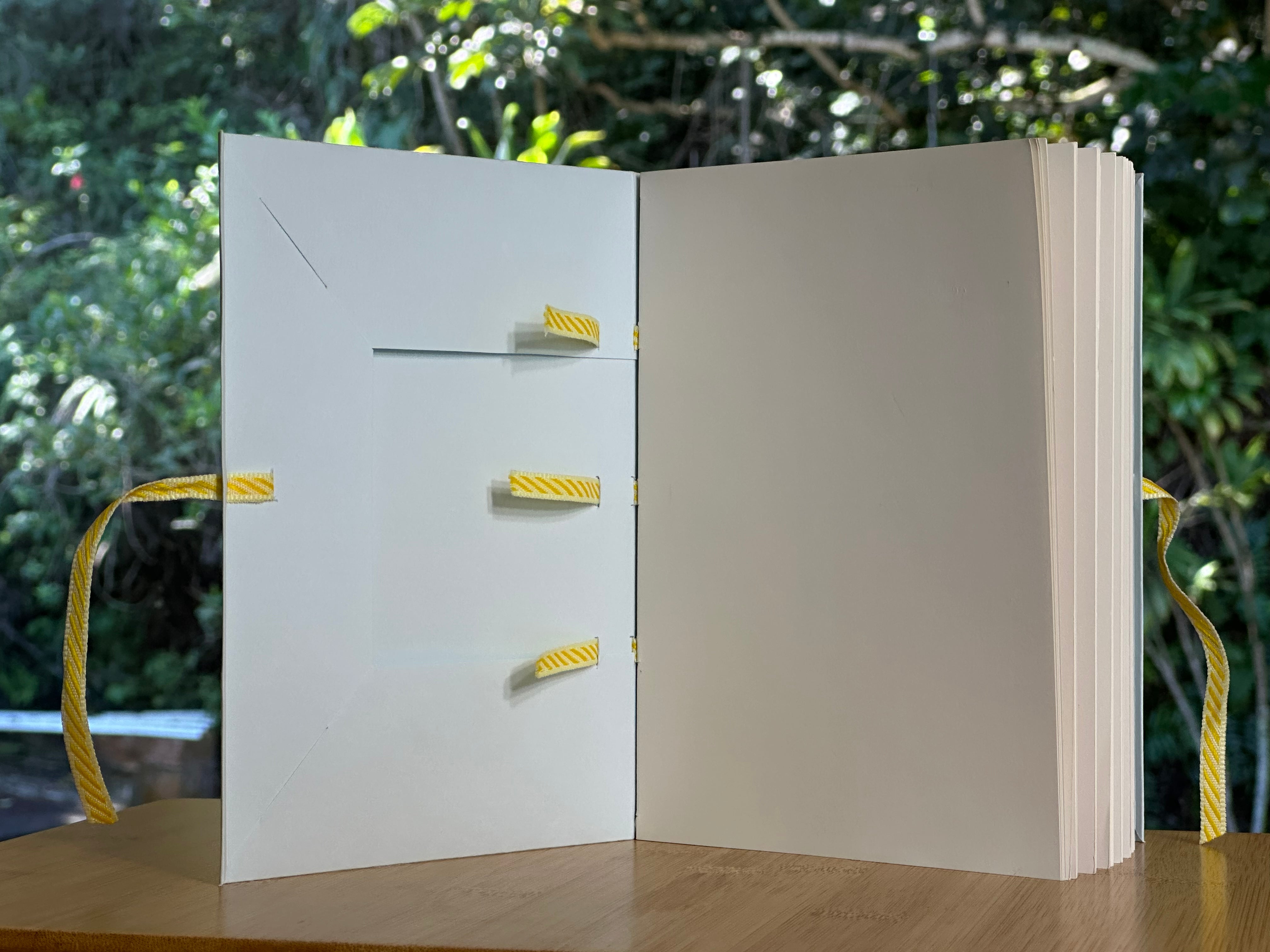 Open Medieval Flexible Binding showing the inside front of the binding on a bamboo table with a forest background