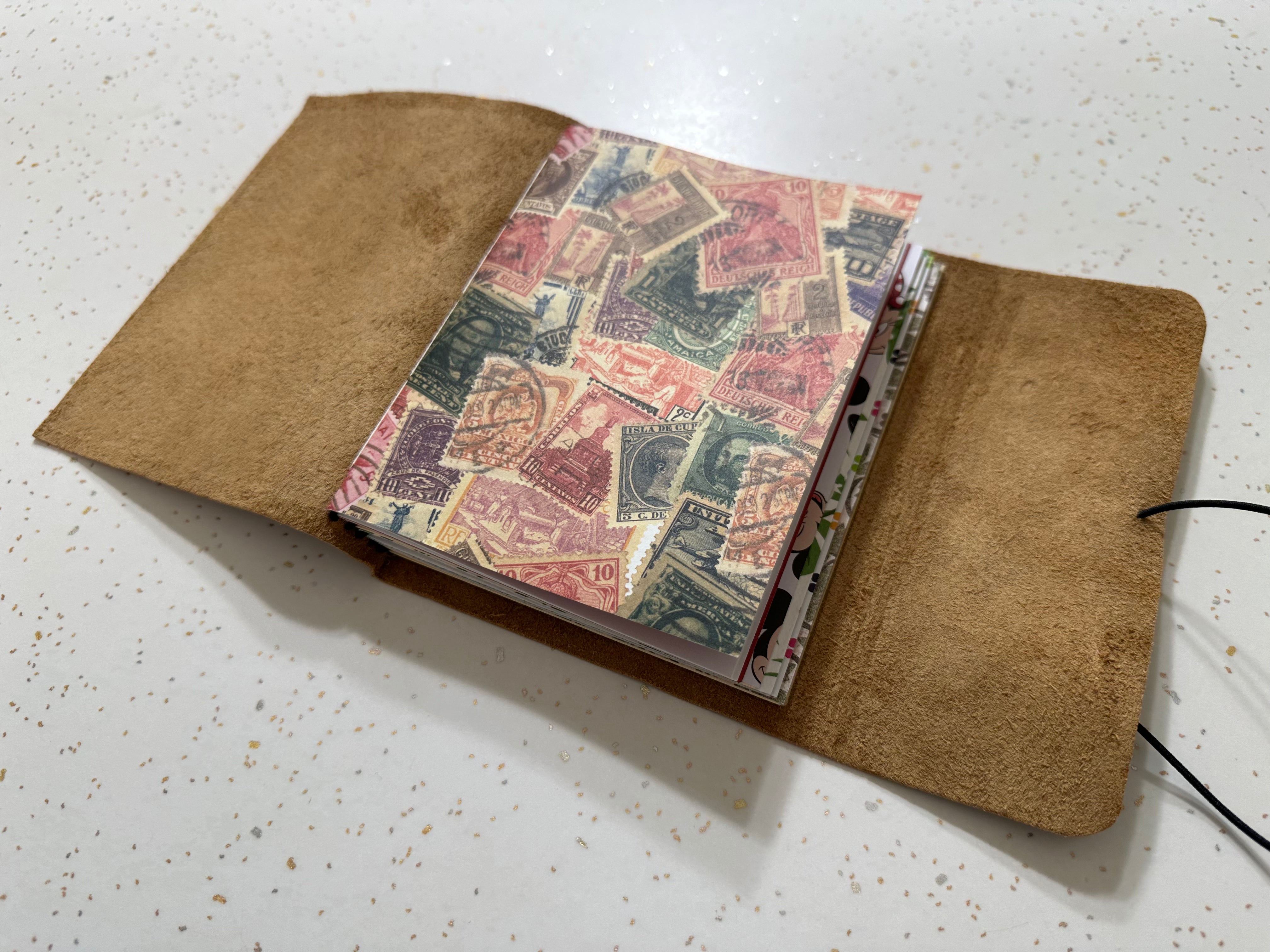 Open notebook with vintage stamp design on a white surface