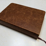 This "after" image showcases a beautifully restored antique book, now featuring a rich brown leather cover with a smooth, reinforced spine and a new ribbon bookmark. Expert book restoration has transformed the fragile, deteriorating volume into a durable and elegant keepsake, preserving its history while enhancing its longevity for generations to come.