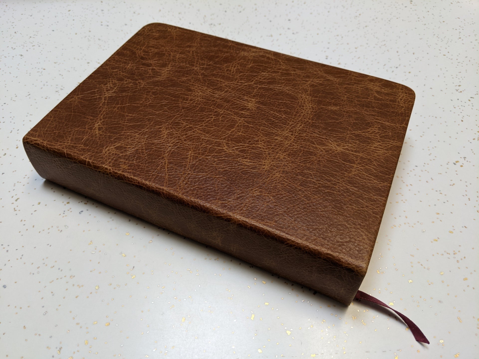 This "after" image showcases a beautifully restored antique book, now featuring a rich brown leather cover with a smooth, reinforced spine and a new ribbon bookmark. Expert book restoration has transformed the fragile, deteriorating volume into a durable and elegant keepsake, preserving its history while enhancing its longevity for generations to come.