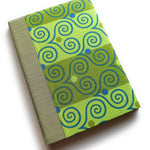 A handmade card with bright green fabric printed with playful blue and olive swirls, paired with a textured sage-green spine -- part of a unique keepsake card collection