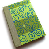 A handmade card with bright green fabric printed with playful blue and olive swirls, paired with a textured sage-green spine -- part of a unique keepsake card collection