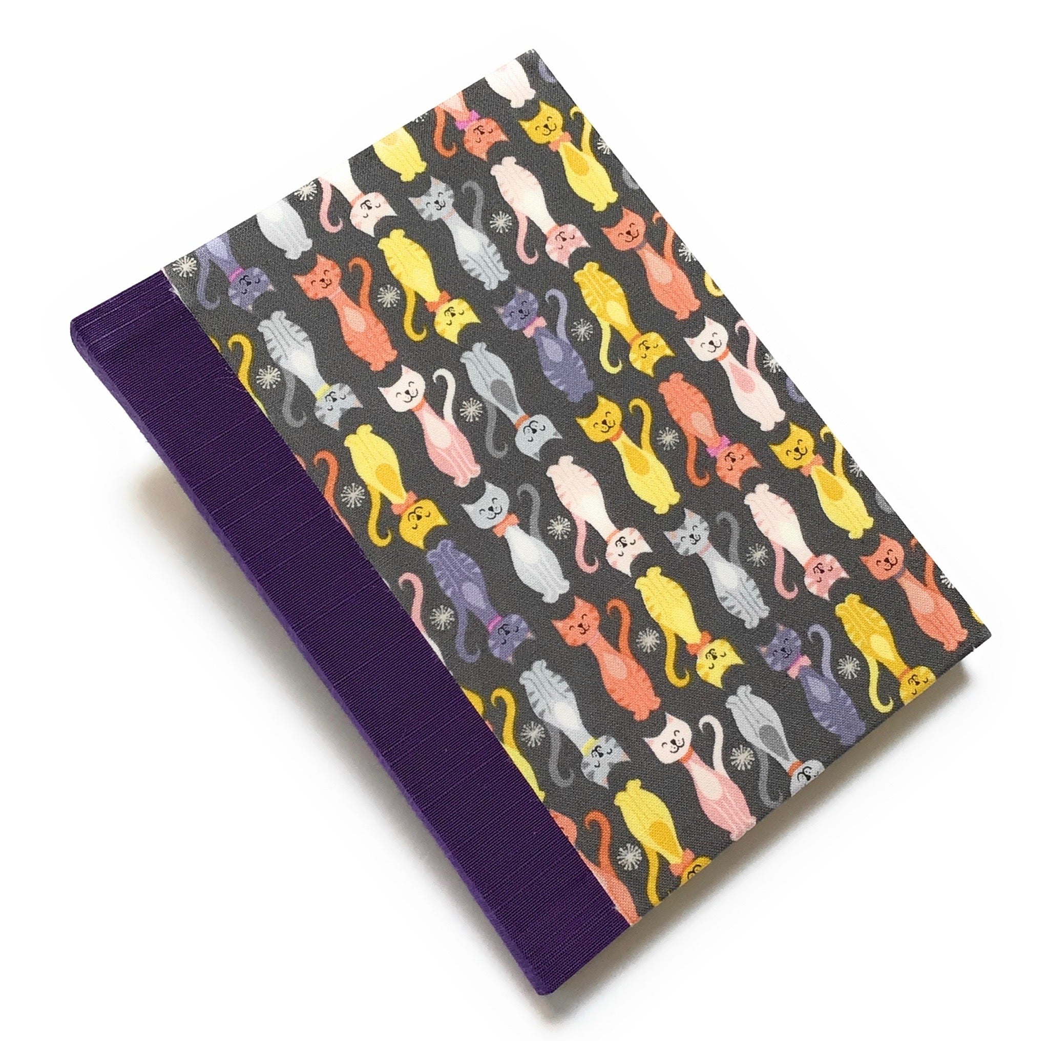 This handmade journal features a charming cat-themed fabric cover with a playful pattern of colorful kittens on a dark background. Designed with high-quality craftsmanship, it’s the perfect notebook for cat lovers, writers, and artists who enjoy capturing their thoughts in a unique and stylish way.