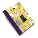 This handmade cat-themed journal features a whimsical fabric cover with a variety of charming cats on a vibrant yellow background. The purple bookbinding cloth spine adds strength, while the blank interior pages provide ample space for journaling, sketching, or note-taking. Perfect for cat lovers, stationery enthusiasts, and those who appreciate unique handmade notebooks, this playful feline journal makes a great gift or personal keepsake.