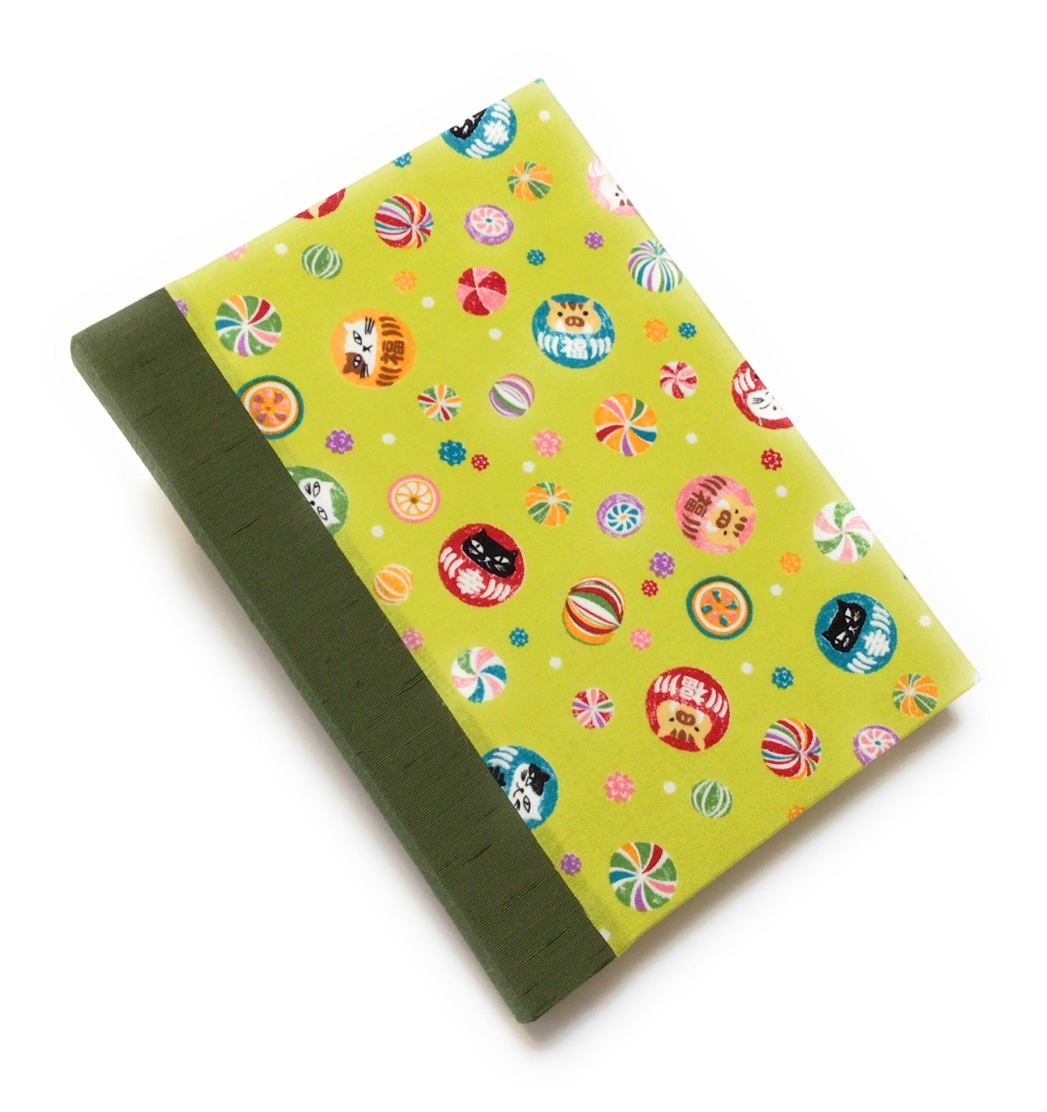 This handmade journal features a lively Japanese-inspired fabric cover adorned with lucky Daruma dolls, playful cat illustrations, and vibrant temari balls on a striking green background. The durable sage green spine adds contrast, making it a perfect notebook for journaling, sketching, or note-taking. Designed for cat lovers and fans of Japanese aesthetics, this unique handcrafted journal is a stylish and functional keepsake.