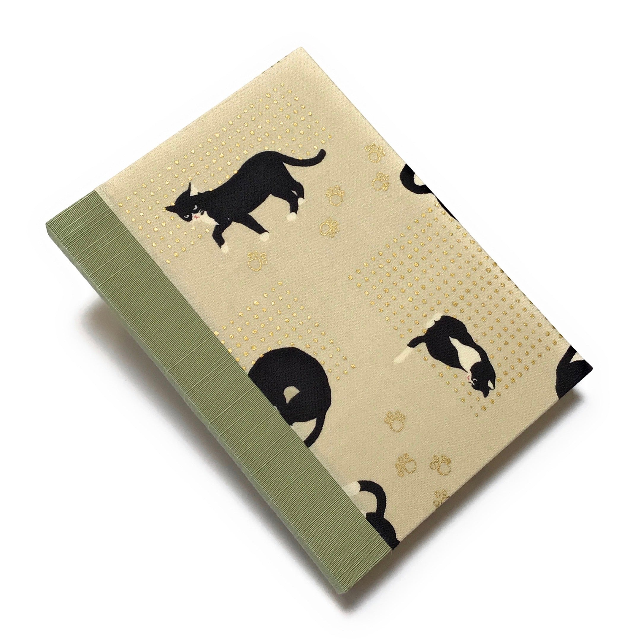 This handcrafted journal features a charming beige fabric cover adorned with playful black tuxedo cats and delicate gold paw prints. The sage green spine adds a natural touch, creating a timeless design perfect for cat lovers, writers, and artists. With high-quality binding and a unique Japanese-inspired aesthetic, this cat-themed notebook makes an excellent gift for journaling, sketching, or daily notes.