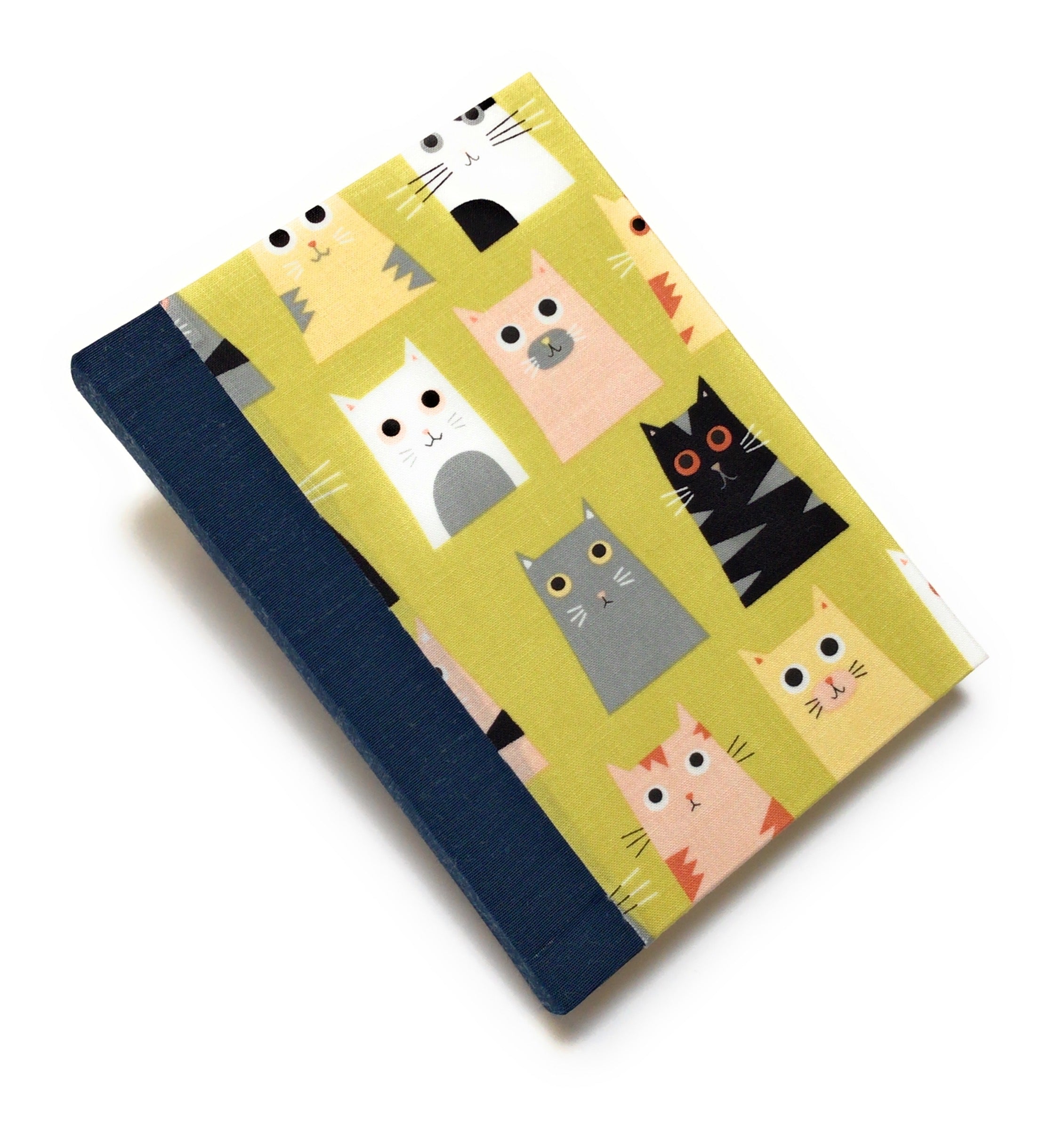 This handmade cat-themed journal features a whimsical fabric cover with a variety of charming cats on a vibrant yellow background. The dark blue bookbinding cloth spine adds strength, while the blank interior pages provide ample space for journaling, sketching, or note-taking. Perfect for cat lovers, stationery enthusiasts, and those who appreciate unique handmade notebooks, this playful feline journal makes a great gift or personal keepsake.