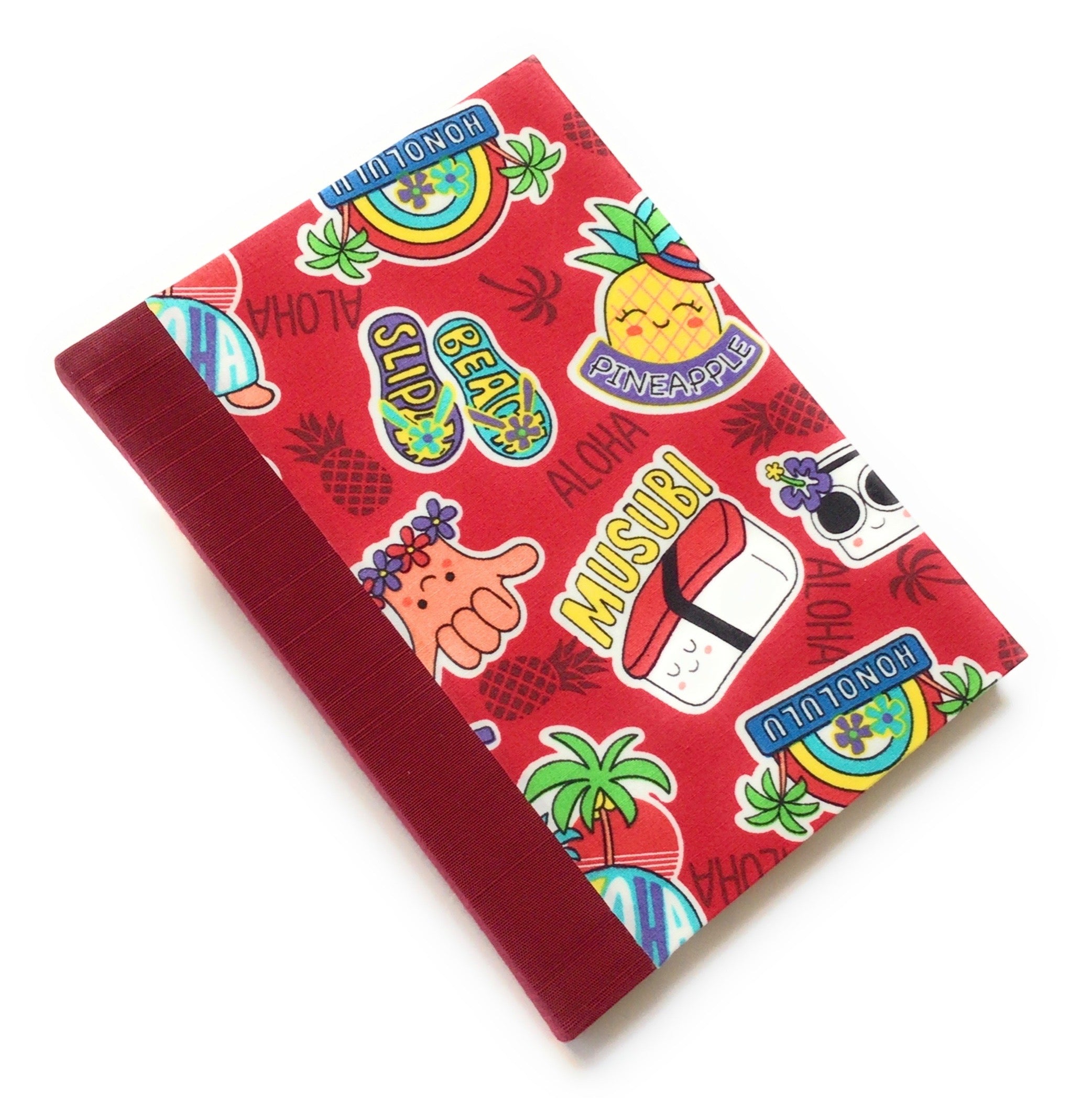 This handmade Aloha Journal features a vibrant red fabric cover decorated with playful Hawaiian-themed illustrations, including musubi, pineapples, beach slippers, and the classic "shaka" hand sign. The durable bookbinding cloth spine ensures longevity, while the blank interior pages provide the perfect space for journaling, sketching, or note-taking. A great choice for lovers of Hawaii-inspired stationery, unique handmade gifts, and island-themed journals.