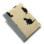 This handcrafted journal features a charming beige fabric cover adorned with playful black tuxedo cats and delicate gold paw prints. The blue gray spine adds a natural touch, creating a timeless design perfect for cat lovers, writers, and artists. With high-quality binding and a unique Japanese-inspired aesthetic, this cat-themed notebook makes an excellent gift for journaling, sketching, or daily notes.