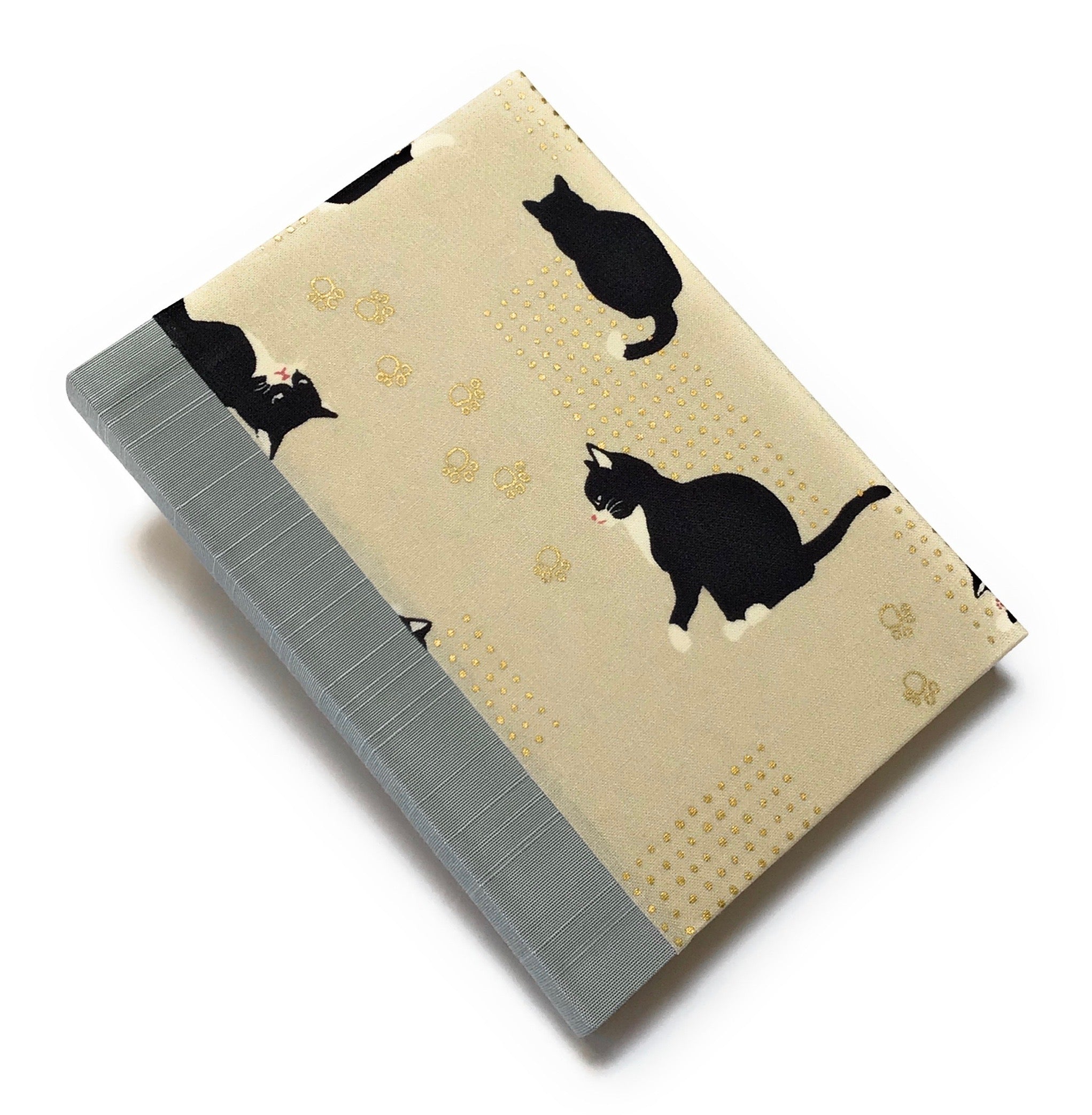 This handcrafted journal features a charming beige fabric cover adorned with playful black tuxedo cats and delicate gold paw prints. The blue gray spine adds a natural touch, creating a timeless design perfect for cat lovers, writers, and artists. With high-quality binding and a unique Japanese-inspired aesthetic, this cat-themed notebook makes an excellent gift for journaling, sketching, or daily notes.