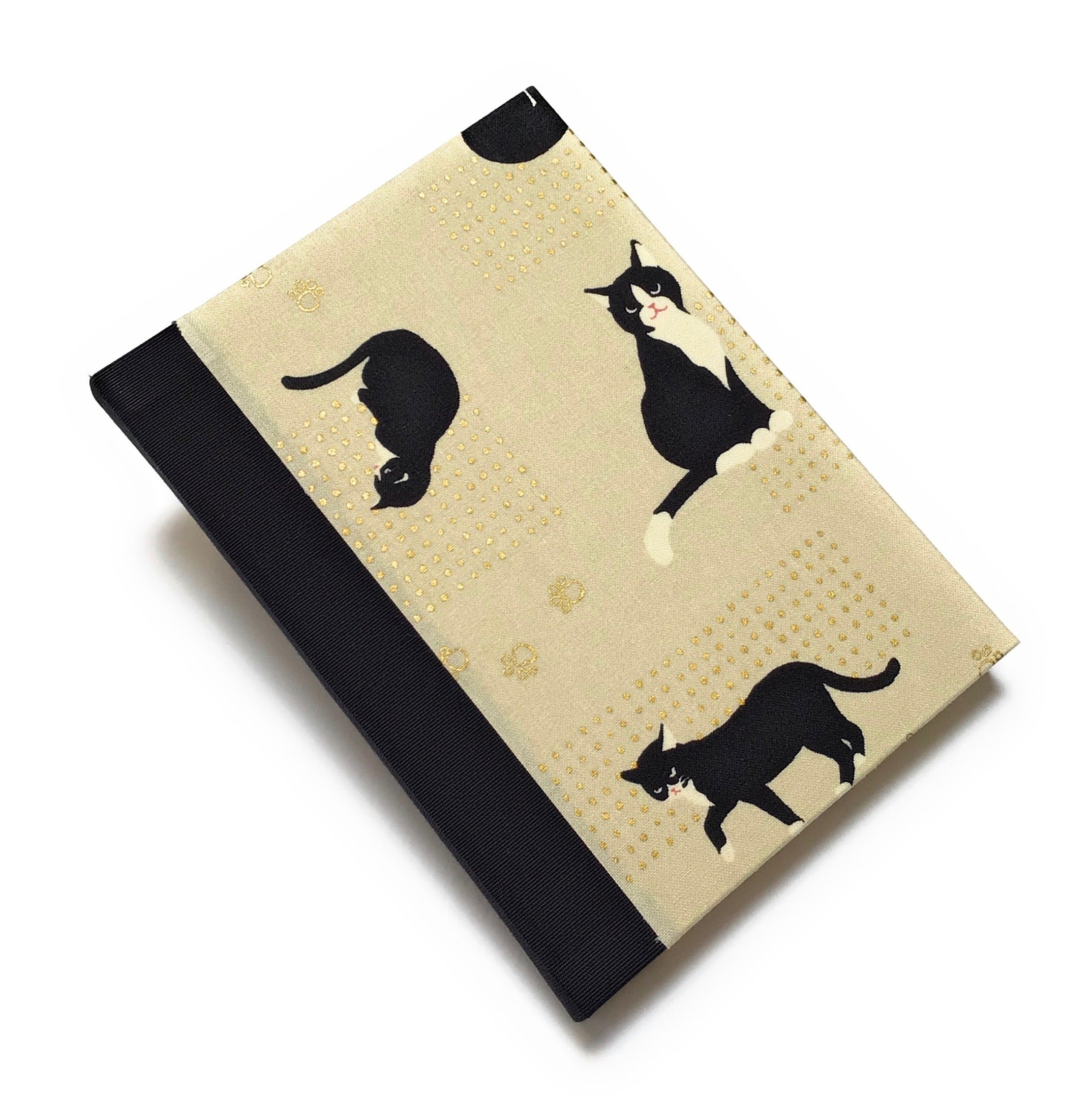 This handcrafted journal features a charming beige fabric cover adorned with playful black tuxedo cats and delicate gold paw prints. The black spine adds a natural touch, creating a timeless design perfect for cat lovers, writers, and artists. With high-quality binding and a unique Japanese-inspired aesthetic, this cat-themed notebook makes an excellent gift for journaling, sketching, or daily notes.