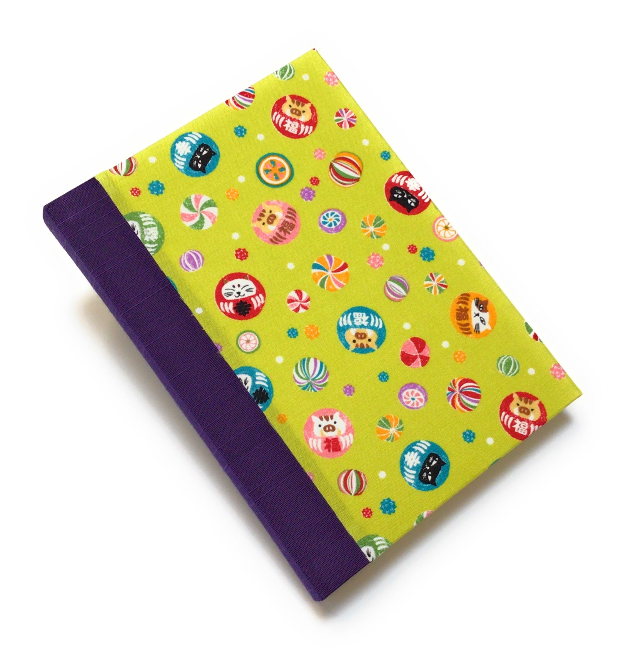 This handmade journal features a lively Japanese-inspired fabric cover adorned with lucky Daruma dolls, playful cat illustrations, and vibrant temari balls on a striking green background. The durable purple spine adds contrast, making it a perfect notebook for journaling, sketching, or note-taking. Designed for cat lovers and fans of Japanese aesthetics, this unique handcrafted journal is a stylish and functional keepsake.