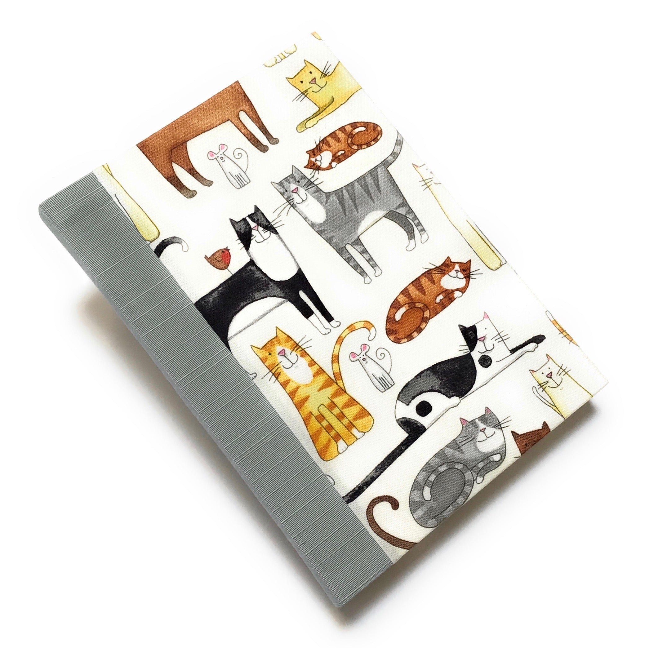 This handmade journal features a delightful fabric cover adorned with playful illustrated cats in various poses, making it a perfect notebook for cat lovers. Bound with a durable blue gray spine and filled with high-quality blank pages, it's an ideal choice for journaling, sketching, or note-taking with a touch of feline charm.